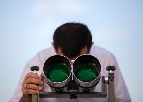 Human looking through extra-large binoculars. Picture represents Elorn's blog post on privacy.